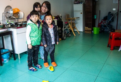 Una mamma con due bimbi e una neonata, cinesi, in cucina all'ex Telecom