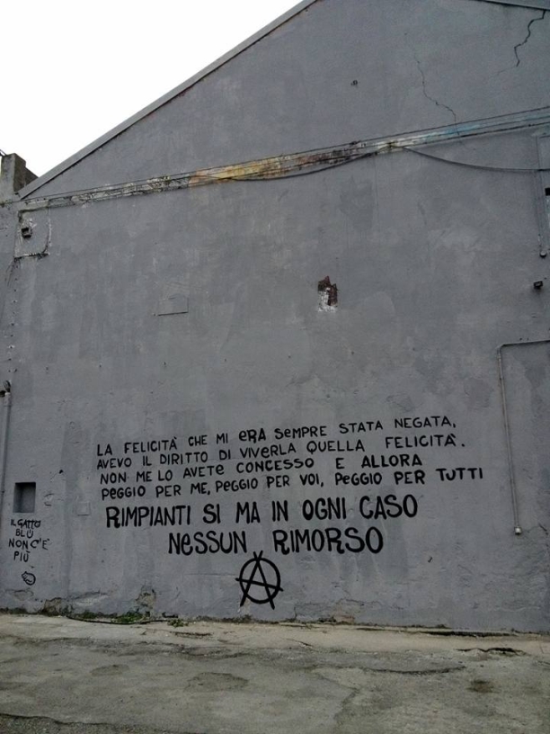 blu scritta anarchica su muro grigio